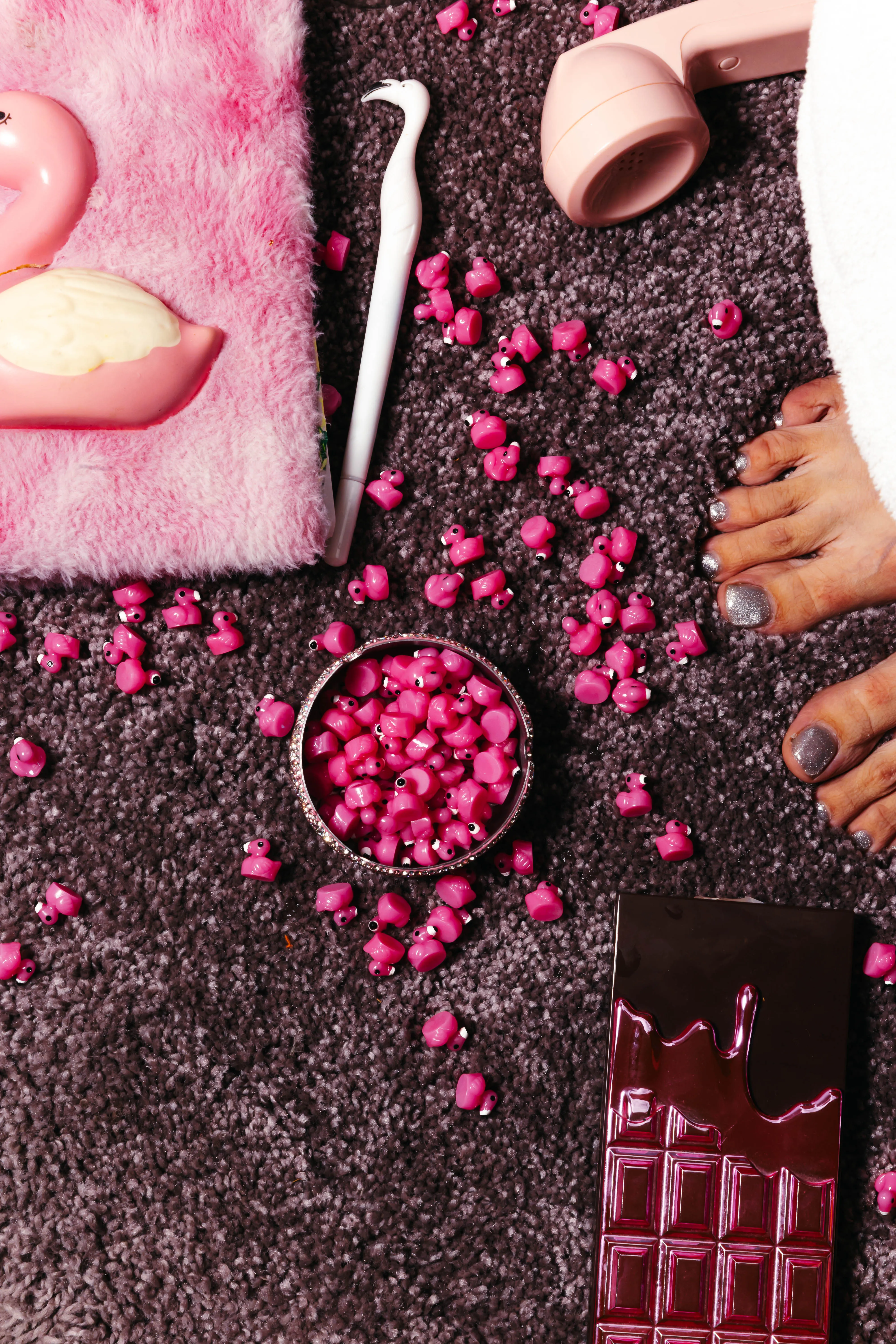 Flat lay of pink accessories and sweets on textured carpet