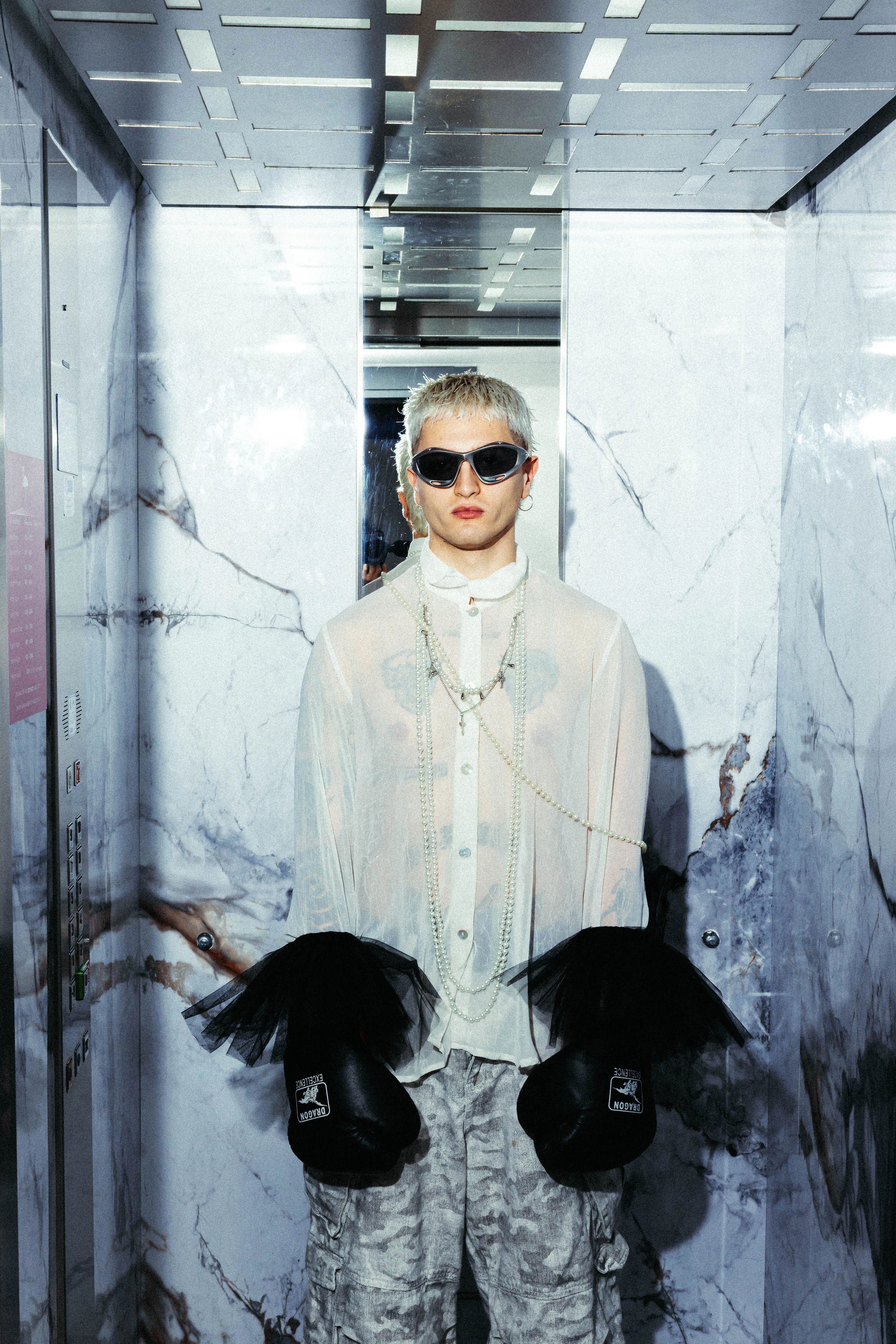 Model with boxing gloves posing in the marble-clad elevator