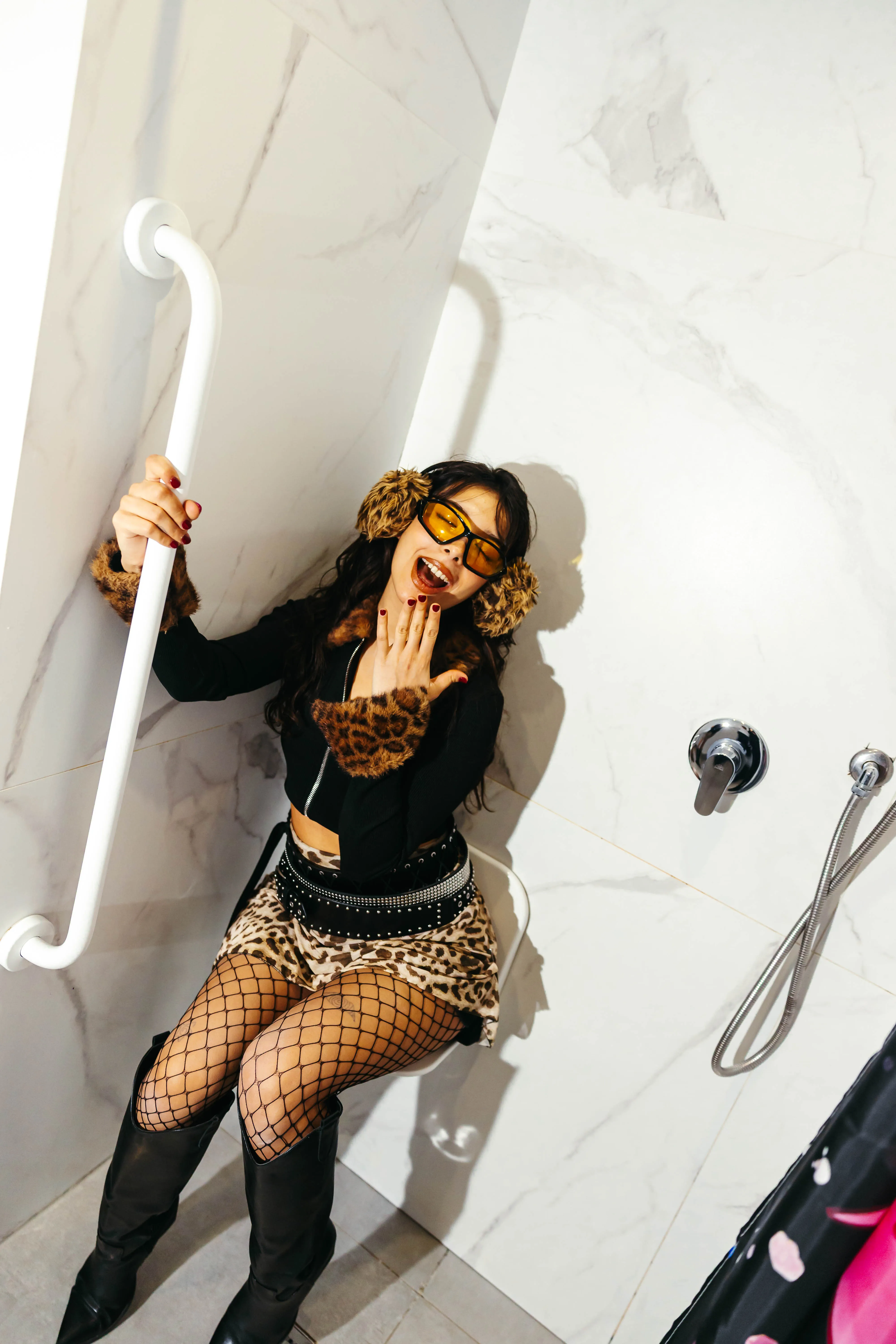 Model laughing in the marble shower with leopard print outfit