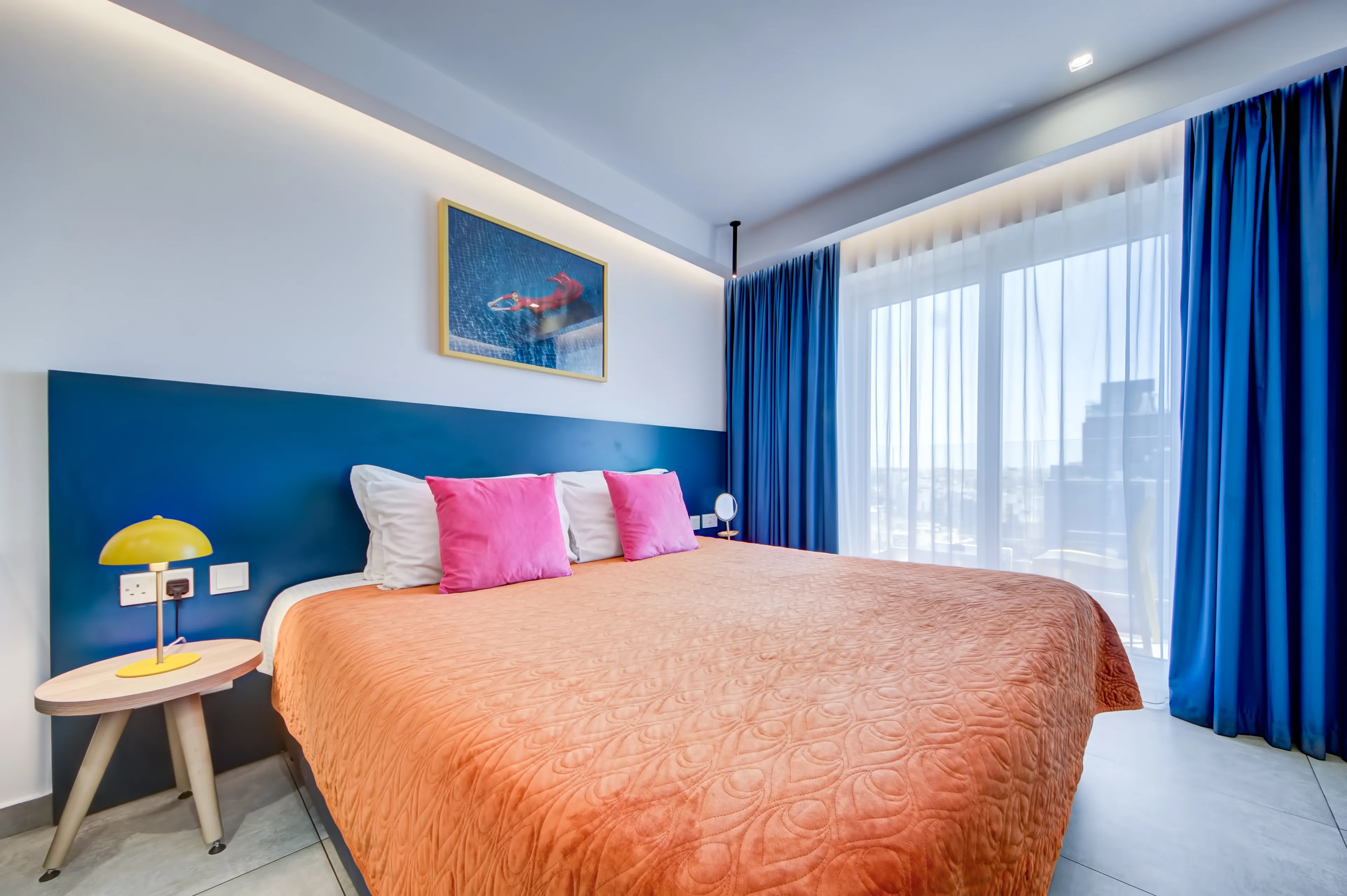 Bedroom with blue headboard and orange bedspread