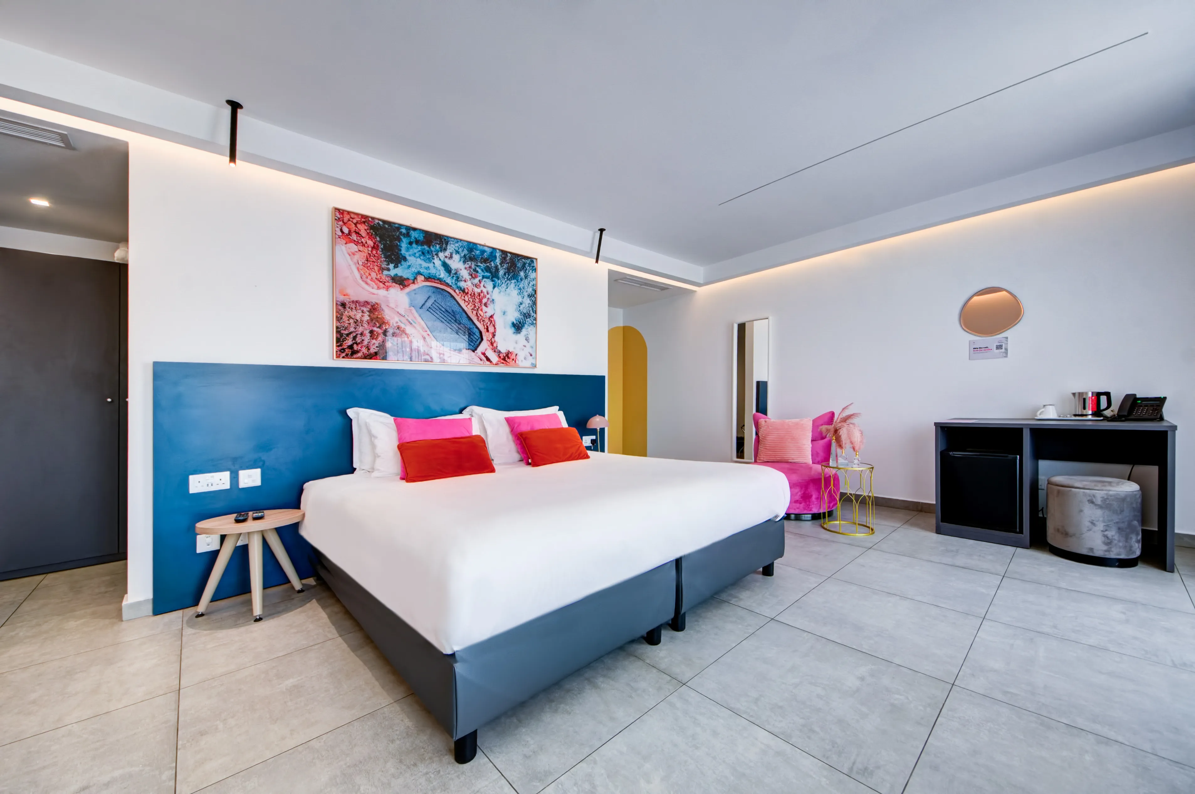 King Suite with blue accent wall, large bed and pink velvet armchair